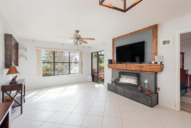 living room featuring ceiling fan, a tile fireplace, and light tile patterned flooring