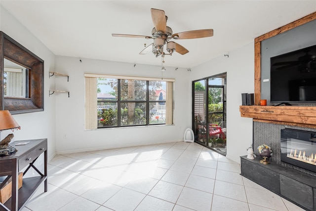 living room featuring a fireplace, light tile patterned flooring, ceiling fan, and a healthy amount of sunlight