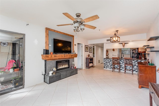 tiled living room with ceiling fan, sink, and a tiled fireplace