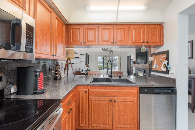 kitchen with appliances with stainless steel finishes, sink, and a stone fireplace