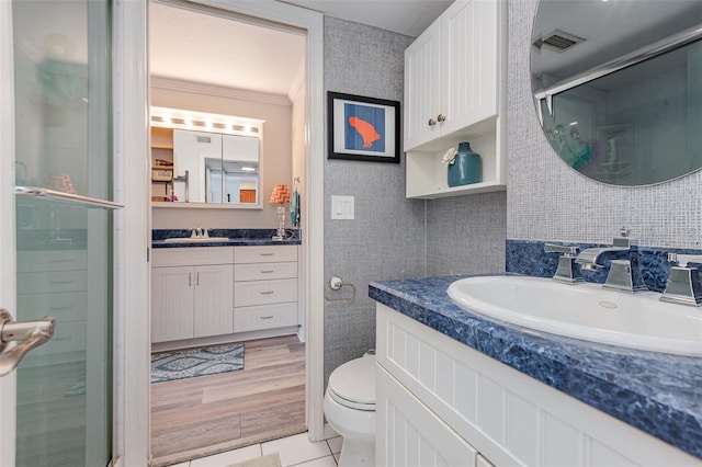 bathroom with tile patterned flooring, vanity, toilet, walk in shower, and crown molding