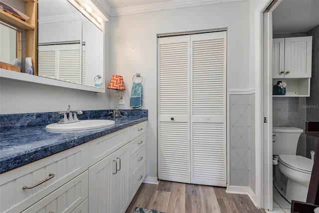 bathroom featuring toilet, ornamental molding, hardwood / wood-style flooring, and vanity