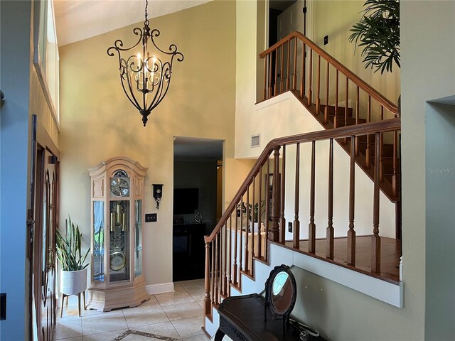 tiled foyer entrance with a towering ceiling and a chandelier