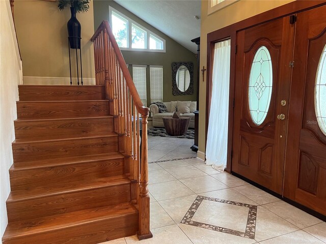 entryway featuring light tile patterned floors and vaulted ceiling