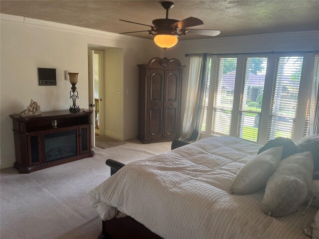 carpeted bedroom featuring a textured ceiling, ceiling fan, and crown molding