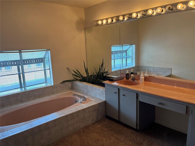 bathroom with vanity and tiled tub