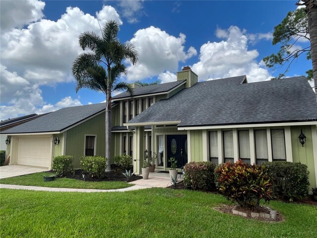 rear view of property featuring a garage and a yard