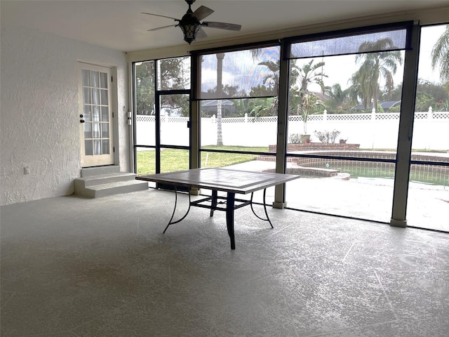 unfurnished sunroom featuring ceiling fan and a water view