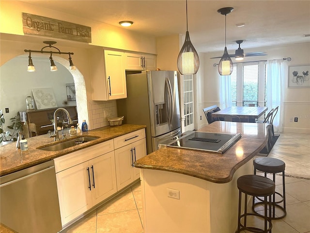 kitchen with stainless steel appliances, sink, pendant lighting, white cabinets, and light tile patterned flooring