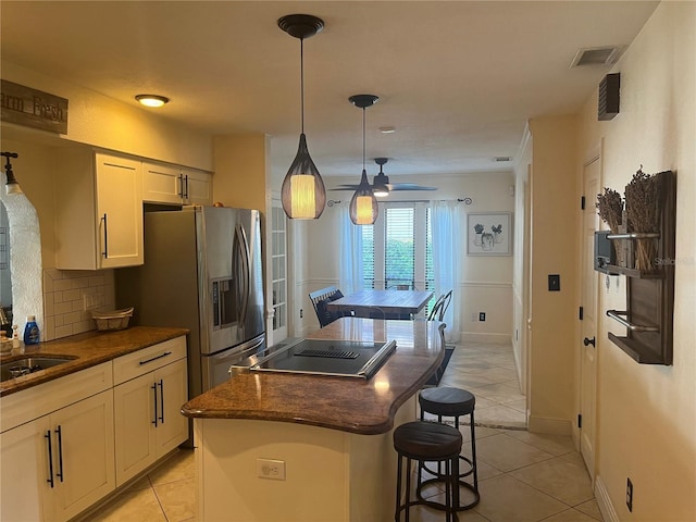 kitchen featuring a breakfast bar area, white cabinetry, a center island, hanging light fixtures, and backsplash