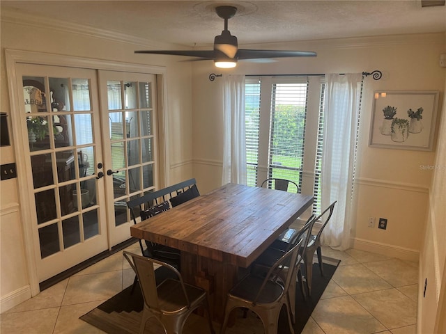 tiled dining room with ceiling fan, ornamental molding, french doors, and a textured ceiling