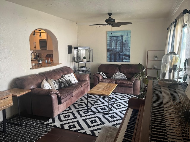 living room with ceiling fan, crown molding, and a textured ceiling