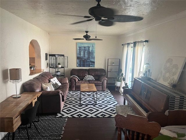 living room with a textured ceiling, dark hardwood / wood-style floors, ceiling fan, and ornamental molding