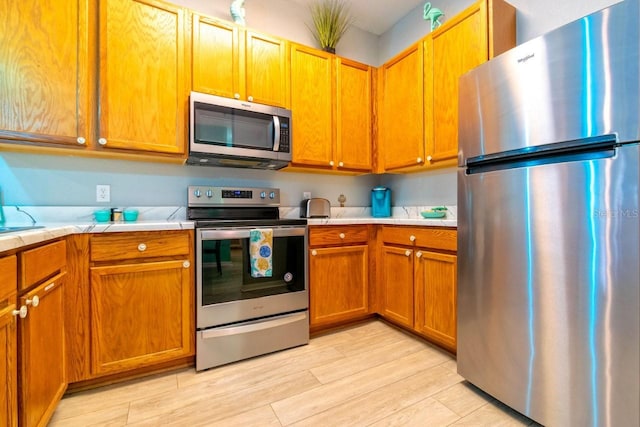 kitchen with appliances with stainless steel finishes and light hardwood / wood-style flooring