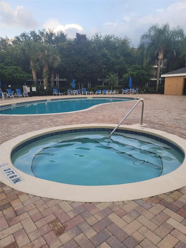 view of swimming pool with a hot tub