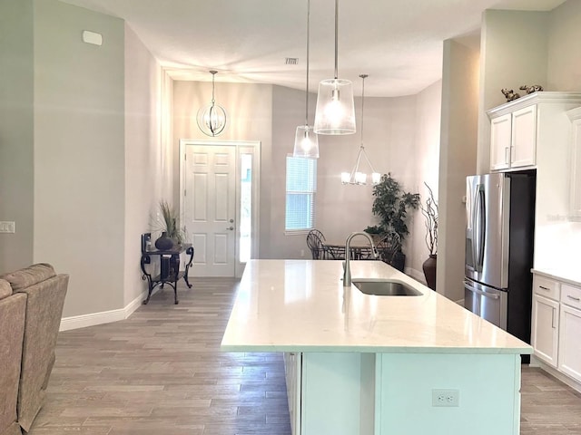 kitchen featuring decorative light fixtures, sink, white cabinetry, stainless steel fridge, and a chandelier