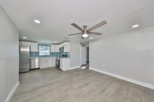 kitchen with light hardwood / wood-style floors, appliances with stainless steel finishes, white cabinetry, and ceiling fan