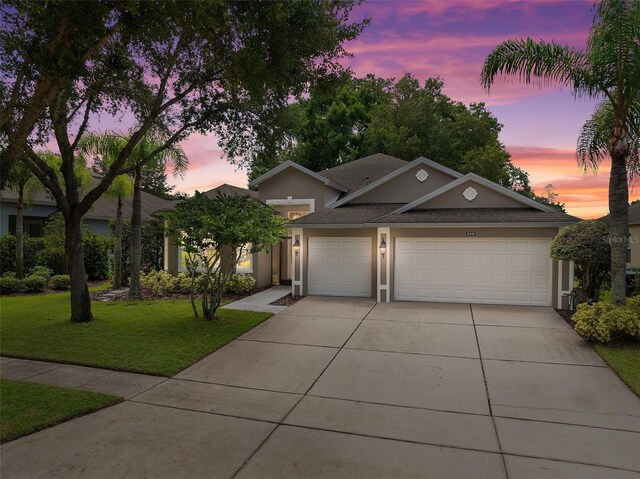 view of front of home with a garage and a lawn