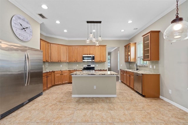 kitchen with light stone countertops, pendant lighting, a kitchen island, stainless steel appliances, and sink