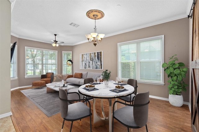 dining space featuring wood-type flooring, ceiling fan with notable chandelier, and ornamental molding