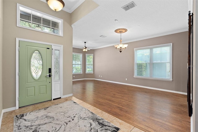 tiled foyer entrance featuring ceiling fan with notable chandelier and ornamental molding