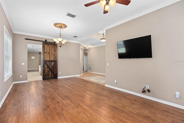 unfurnished living room with ceiling fan with notable chandelier, wood-type flooring, ornamental molding, and a barn door