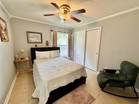 tiled bedroom with ornamental molding, a textured ceiling, a closet, and ceiling fan