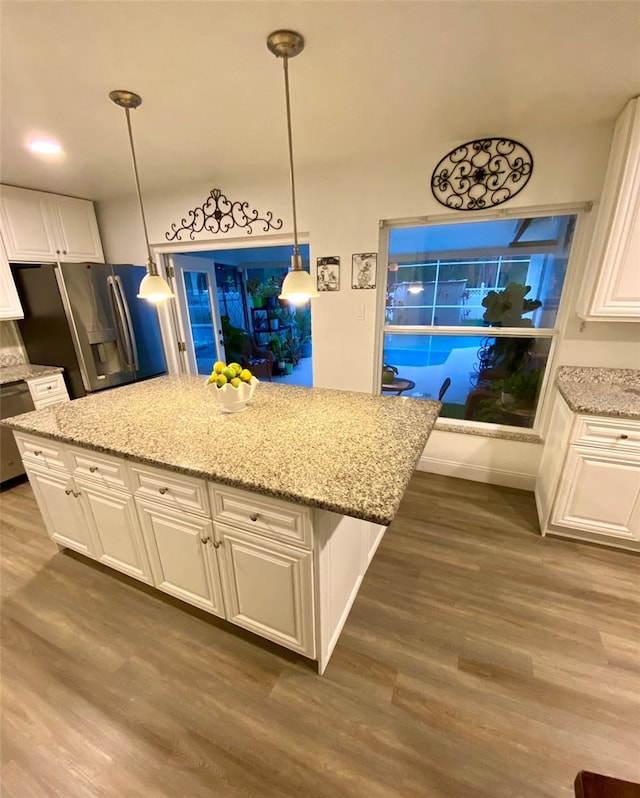 kitchen featuring dark hardwood / wood-style floors, hanging light fixtures, stainless steel appliances, light stone countertops, and white cabinets