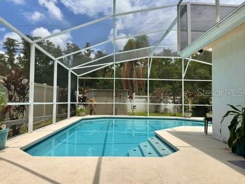 view of swimming pool featuring a patio area and glass enclosure