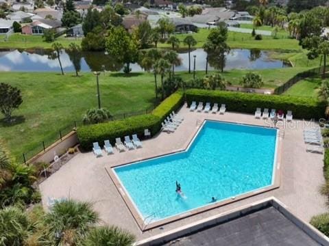 view of pool with a water view, a patio, and a yard