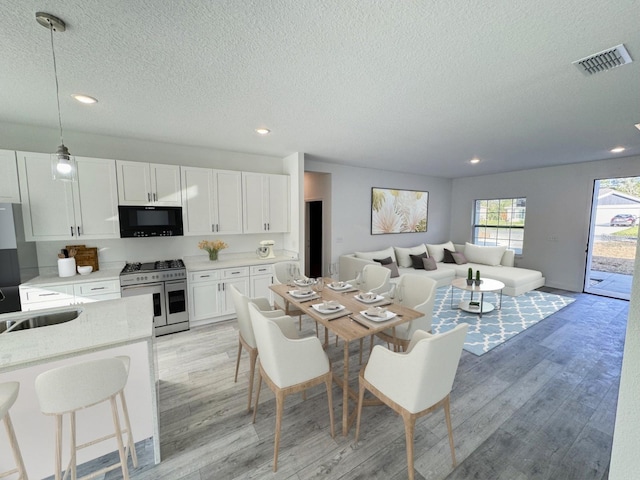 dining space featuring sink, light hardwood / wood-style flooring, and a textured ceiling