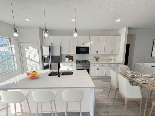 kitchen featuring white cabinets, stainless steel appliances, sink, and an island with sink