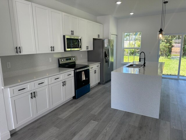 kitchen with sink, white cabinetry, decorative light fixtures, an island with sink, and stainless steel appliances