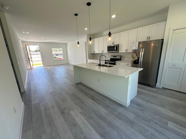 kitchen with white cabinetry, stainless steel appliances, sink, and pendant lighting