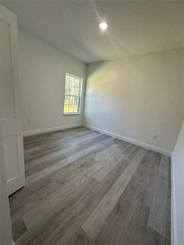 unfurnished room featuring light hardwood / wood-style floors and a textured ceiling