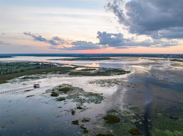 aerial view at dusk featuring a water view