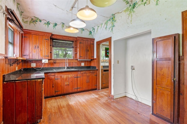 kitchen with pendant lighting, sink, and light wood-type flooring