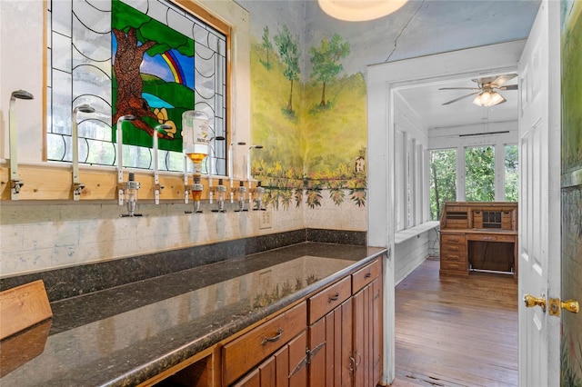 bar with dark stone countertops, wood-type flooring, tasteful backsplash, and ceiling fan