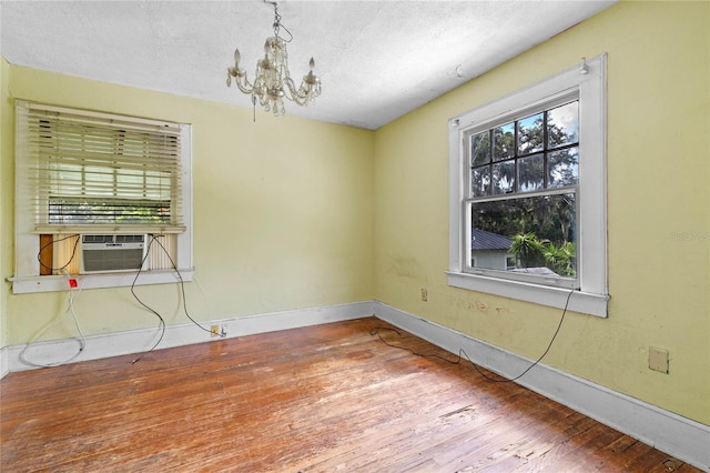 unfurnished room with hardwood / wood-style floors, a textured ceiling, and a chandelier