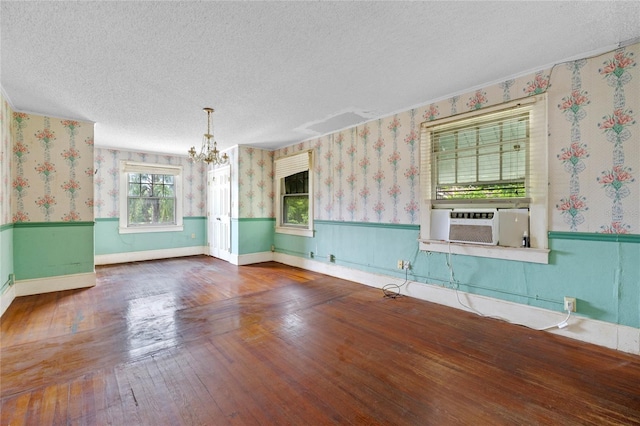 spare room with cooling unit, a notable chandelier, hardwood / wood-style flooring, and a textured ceiling