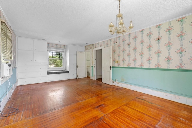 unfurnished room featuring wood-type flooring, a textured ceiling, and a notable chandelier