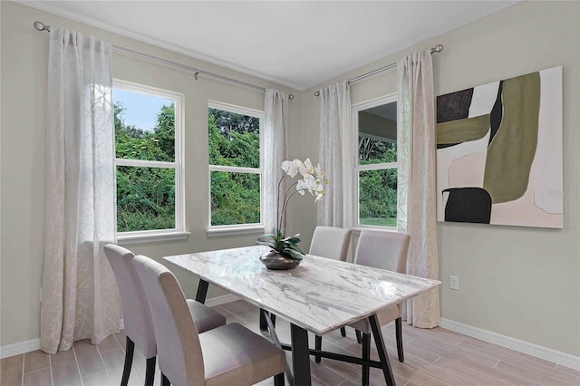 dining area with baseboards, wood tiled floor, and a healthy amount of sunlight