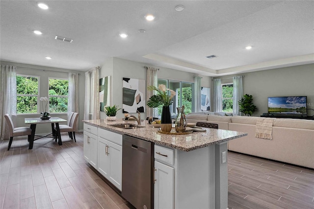 kitchen with a sink, white cabinets, open floor plan, dishwasher, and an island with sink