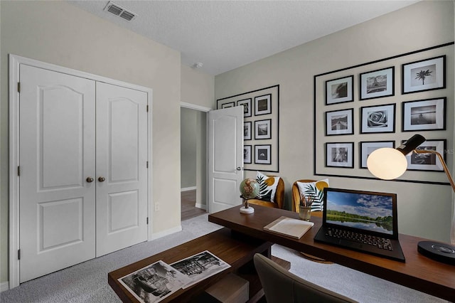 office area with carpet, visible vents, a textured ceiling, and baseboards