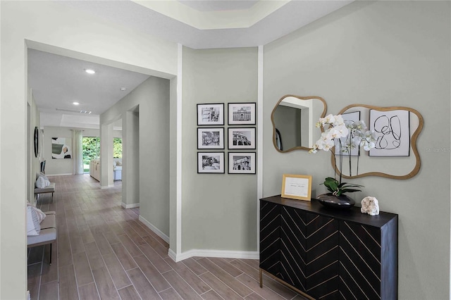 corridor featuring wood finish floors, recessed lighting, and baseboards