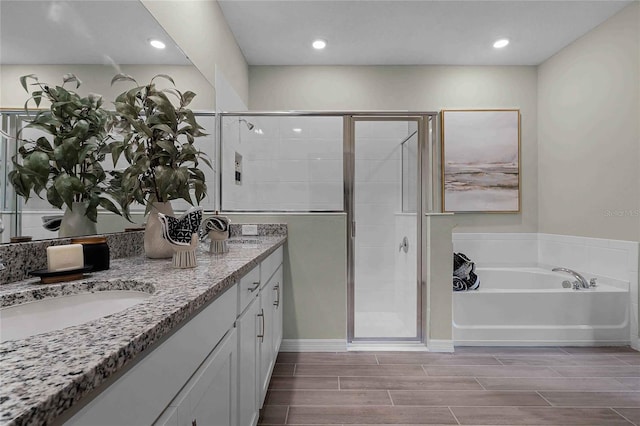 bathroom with a garden tub, a sink, a shower stall, wood tiled floor, and double vanity