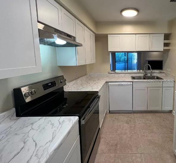 kitchen featuring light tile patterned floors, white cabinets, dishwasher, electric stove, and sink