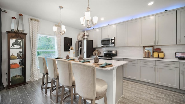 kitchen featuring appliances with stainless steel finishes, a kitchen bar, decorative backsplash, and a kitchen island with sink