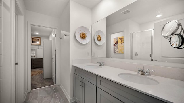 bathroom featuring dual vanity, a shower with door, and tile patterned floors