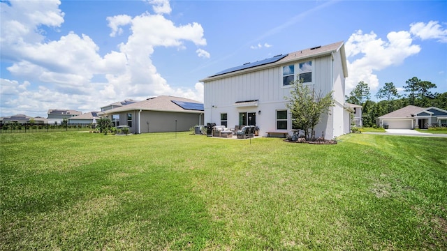 rear view of house with a garage, a yard, and solar panels